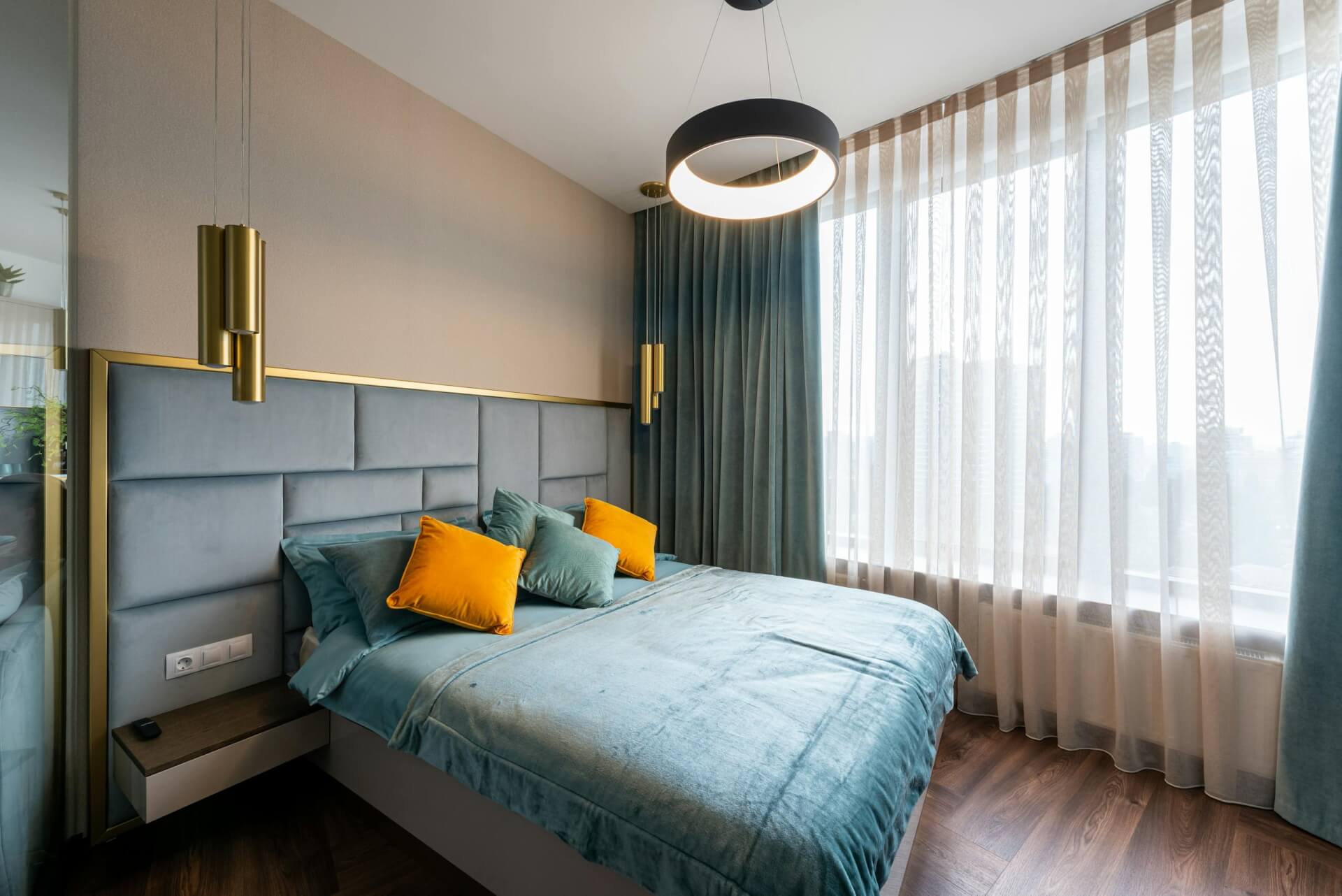 A stylish bedroom featuring turquoise decor, gold accents, and chic lighting.