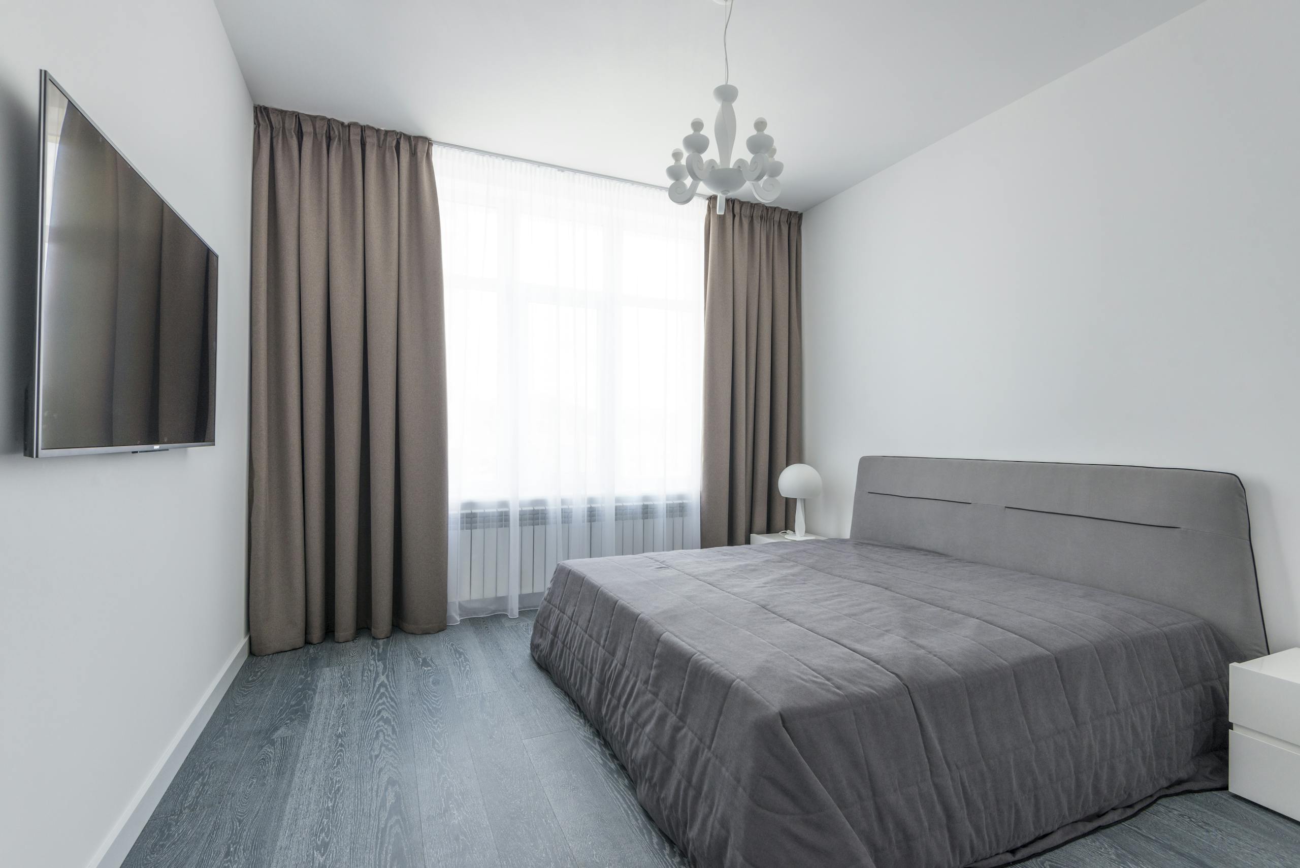 A sleek and modern minimalist bedroom featuring neutral tones and natural light.